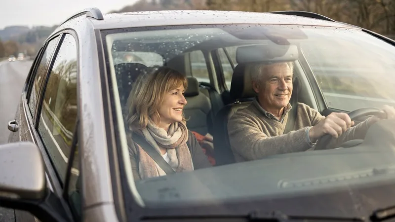 Mature couple driving, the man at the wheel, both looking ahead